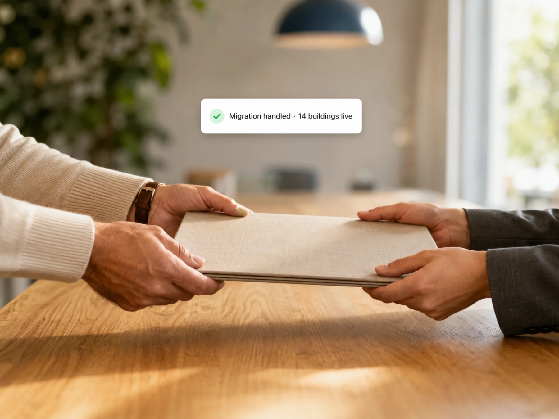 A folder being handed across a meeting table — migration handled, 14 buildings live